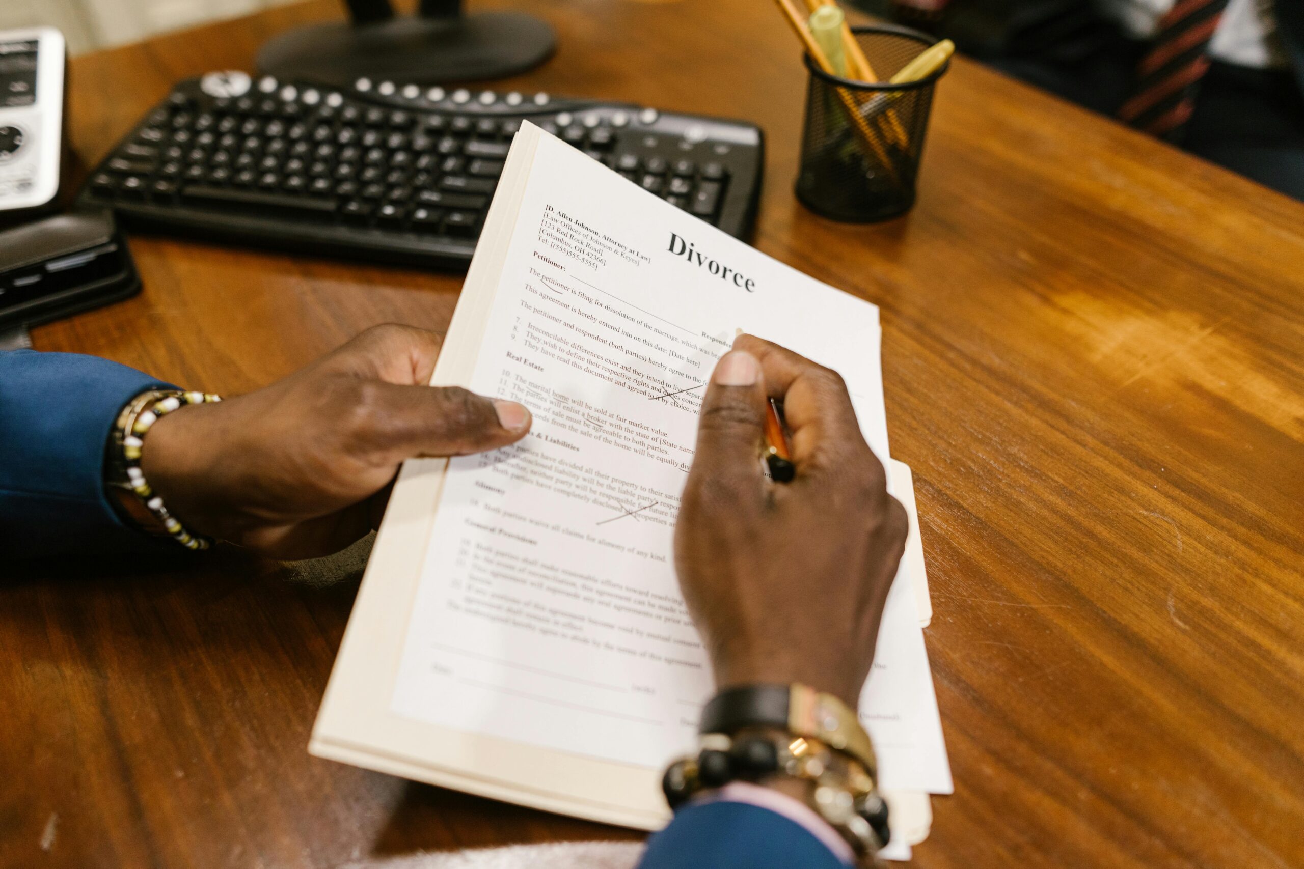 A person signs official divorce documents at an office desk.